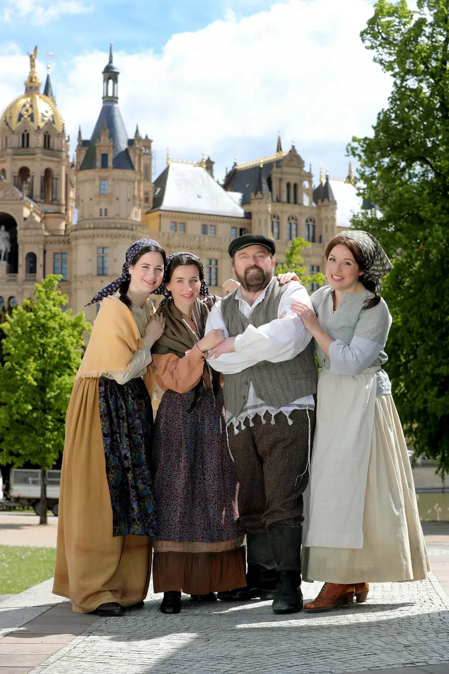 Die Darsteller des Stückes „Anatevka“ vor dem Schweriner Schloss: v. l. n. r.: Irene Eggerstorfer, Katrin Hübner, Gustav Peter Wöhler, Nedime Ostheimer.
